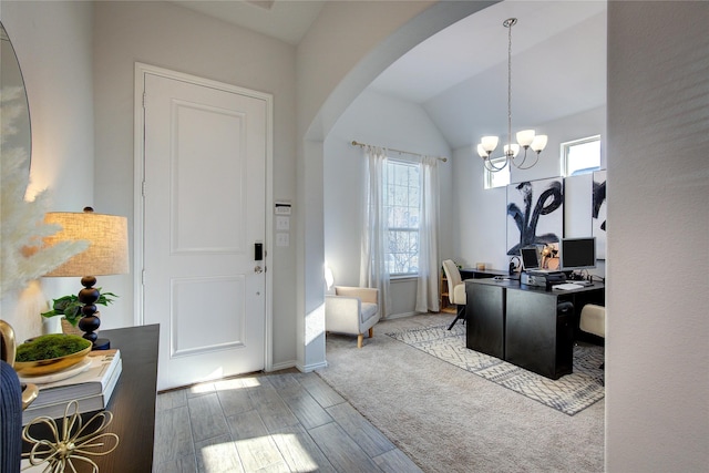 office space with a healthy amount of sunlight, an inviting chandelier, lofted ceiling, and light hardwood / wood-style flooring