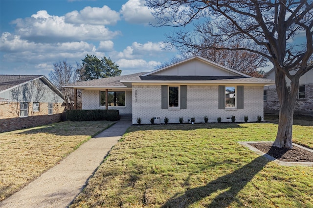 ranch-style home with a front lawn, brick siding, and roof with shingles