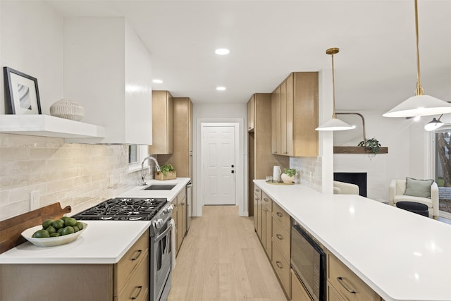 kitchen with decorative light fixtures, tasteful backsplash, sink, stainless steel gas range, and light wood-type flooring