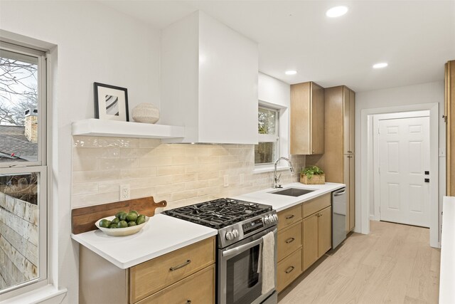 kitchen with light hardwood / wood-style floors, sink, stainless steel appliances, and tasteful backsplash