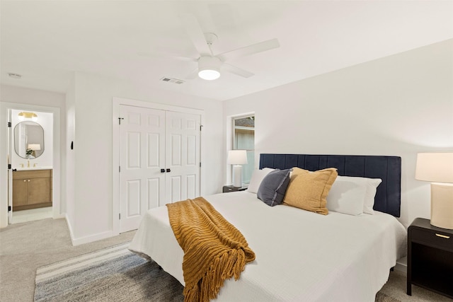 carpeted bedroom featuring sink, a closet, ceiling fan, and ensuite bathroom