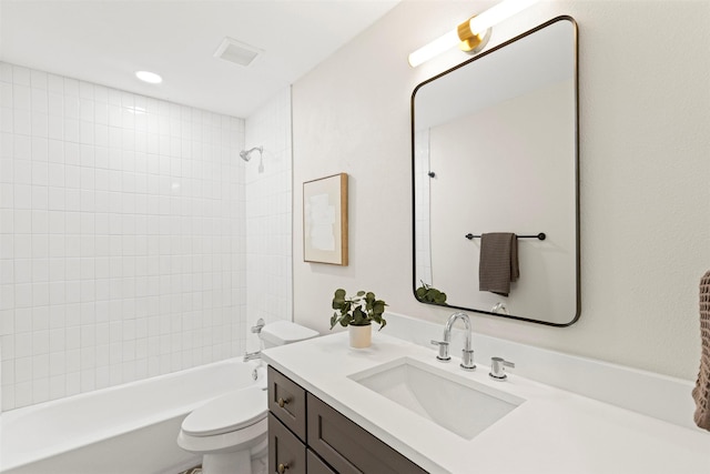 full bathroom featuring vanity, tiled shower / bath combo, and toilet