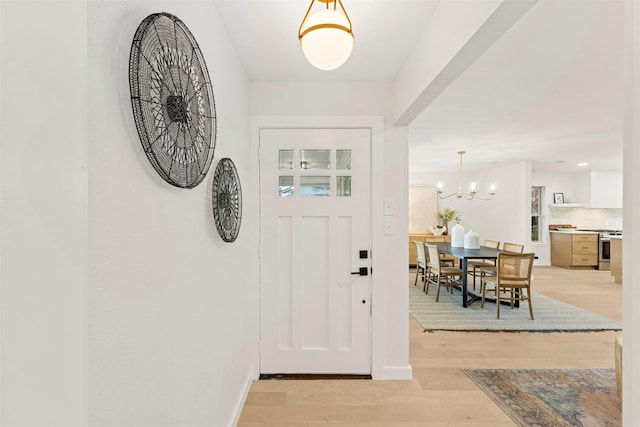 entryway with an inviting chandelier and light wood-type flooring