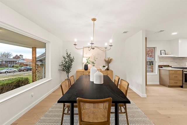 dining space with light hardwood / wood-style flooring and a chandelier