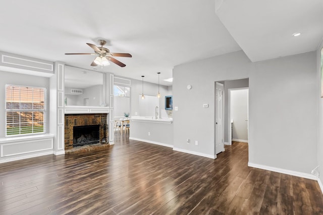 unfurnished living room with ceiling fan, sink, and dark wood-type flooring