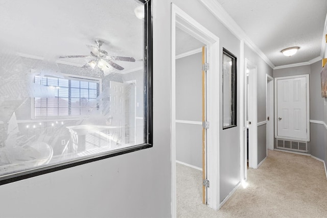 corridor with a textured ceiling, light colored carpet, and crown molding