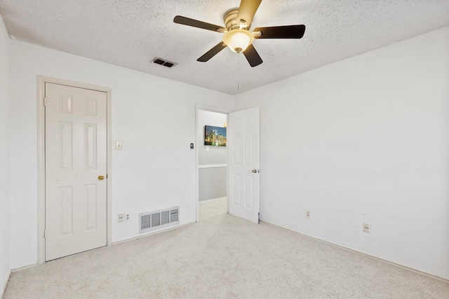 unfurnished bedroom featuring light carpet, a textured ceiling, and ceiling fan