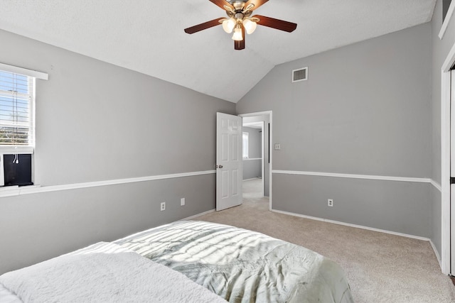 bedroom featuring a textured ceiling, light colored carpet, ceiling fan, and lofted ceiling