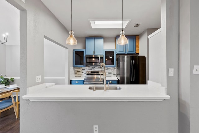 kitchen with kitchen peninsula, decorative backsplash, blue cabinets, and appliances with stainless steel finishes