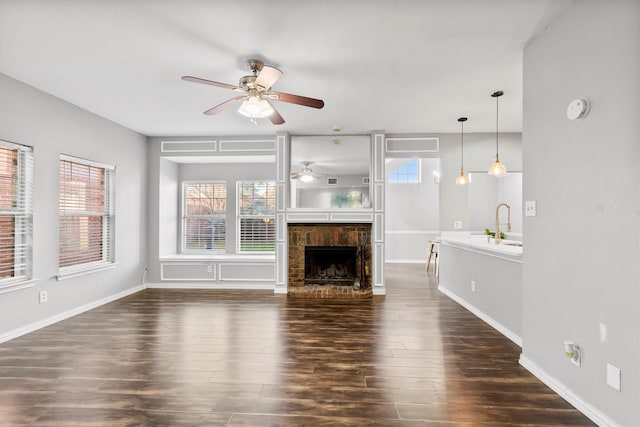 unfurnished living room with dark hardwood / wood-style floors, ceiling fan, and sink