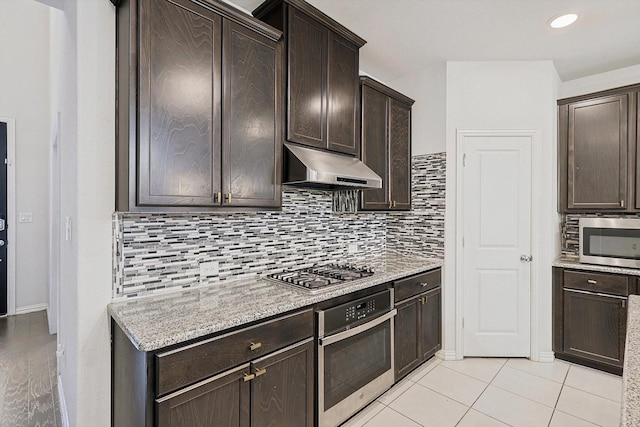 kitchen with backsplash, dark brown cabinets, light tile patterned floors, and appliances with stainless steel finishes