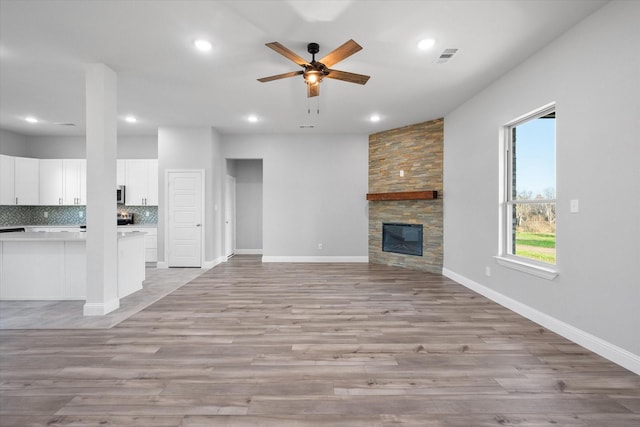 unfurnished living room with light hardwood / wood-style flooring, a fireplace, and ceiling fan