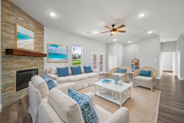 living room with wood-type flooring, ceiling fan, a fireplace, and french doors