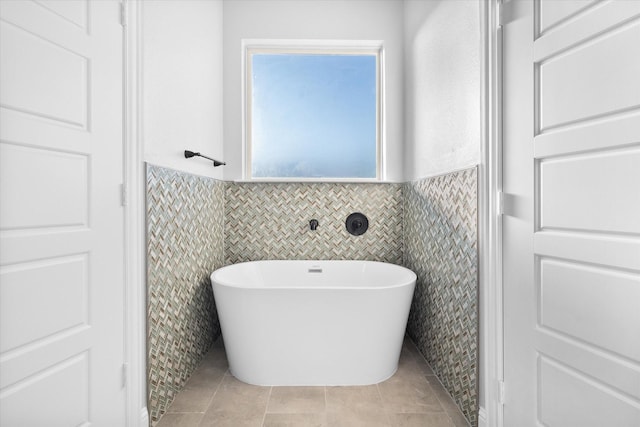 bathroom with tile patterned flooring, tile walls, and a washtub