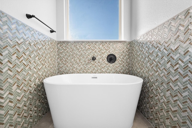 bathroom with tile patterned flooring, tile walls, and a washtub