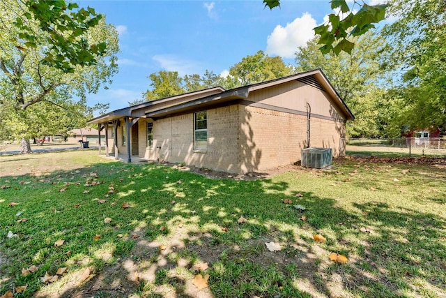 view of side of property with central AC unit and a yard