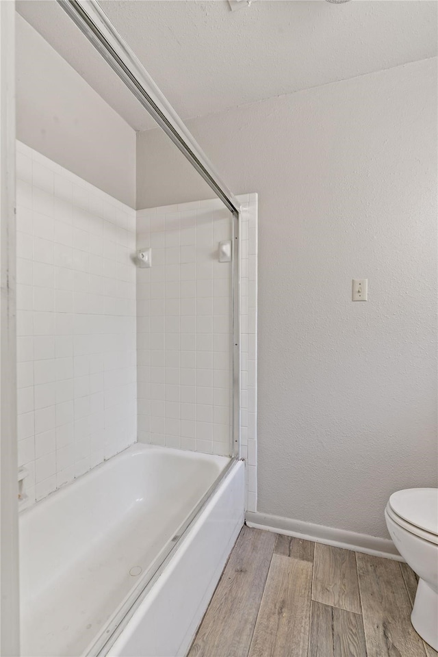 bathroom featuring tiled shower / bath combo, hardwood / wood-style floors, and toilet