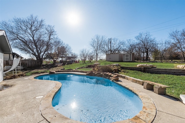 view of pool with a patio, a lawn, and a storage shed