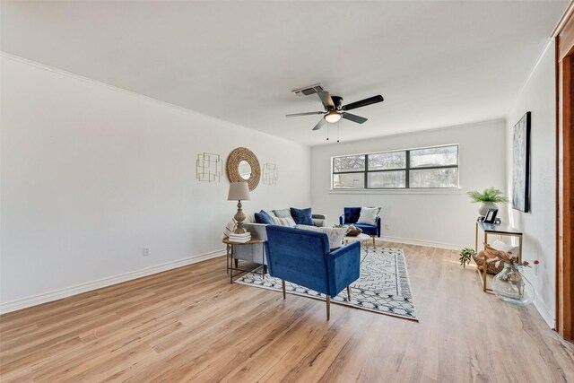 living room with ceiling fan, light wood-type flooring, and ornamental molding