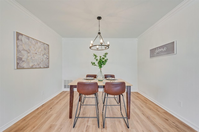 dining space featuring a notable chandelier, ornamental molding, and light wood-type flooring