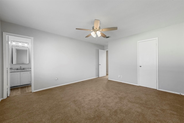 unfurnished bedroom with connected bathroom, ceiling fan, sink, a closet, and dark carpet