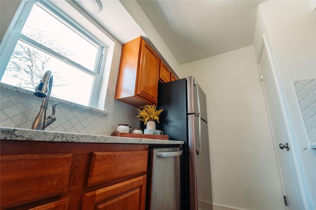 kitchen featuring stainless steel refrigerator, light stone countertops, and decorative backsplash