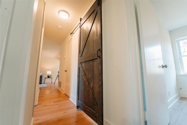 hallway with a barn door and light hardwood / wood-style floors