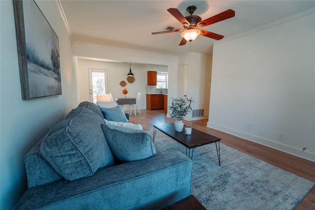 living room featuring hardwood / wood-style flooring, crown molding, and ceiling fan