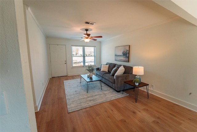 living room featuring ornamental molding, ceiling fan, and light wood-type flooring