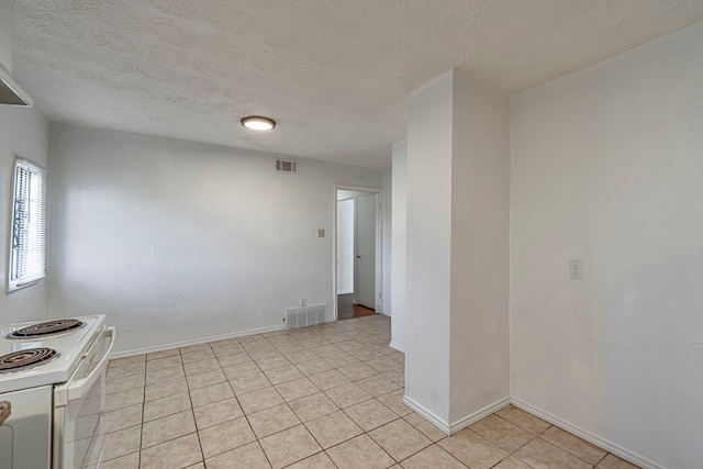 spare room with a textured ceiling and light tile patterned flooring