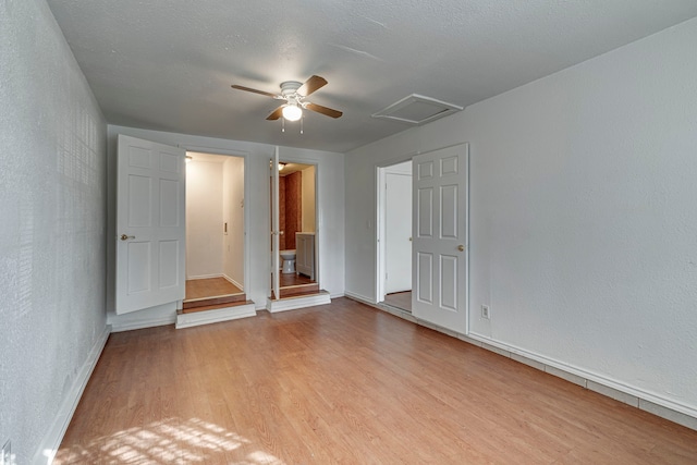 empty room with a textured ceiling, ceiling fan, and light wood-type flooring