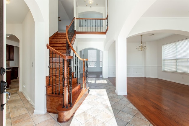 staircase with a chandelier, hardwood / wood-style floors, and ornamental molding