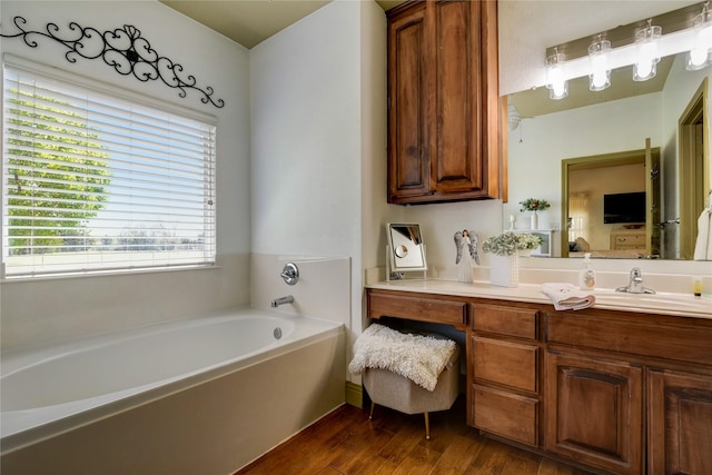 bathroom with hardwood / wood-style flooring, vanity, and a bath