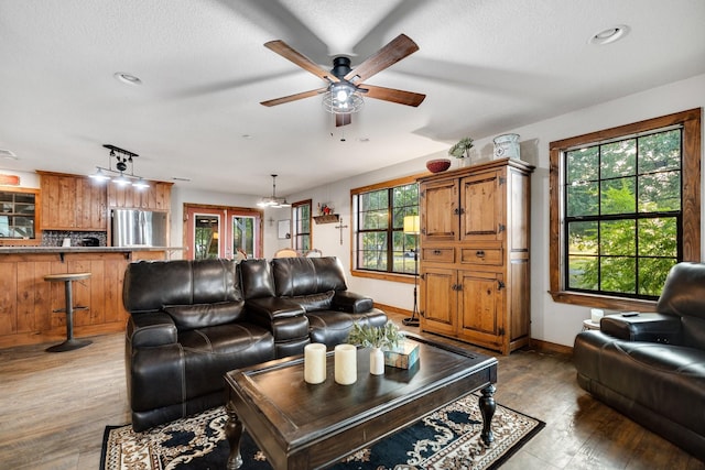 living room featuring hardwood / wood-style flooring, ceiling fan, and a textured ceiling