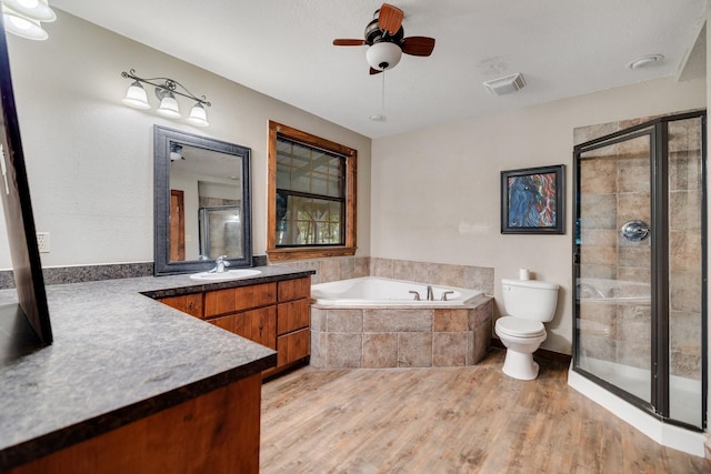 full bathroom featuring ceiling fan, hardwood / wood-style floors, vanity, shower with separate bathtub, and toilet