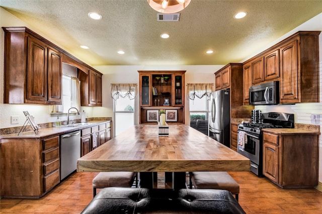 kitchen with sink, a wealth of natural light, light hardwood / wood-style flooring, and stainless steel appliances