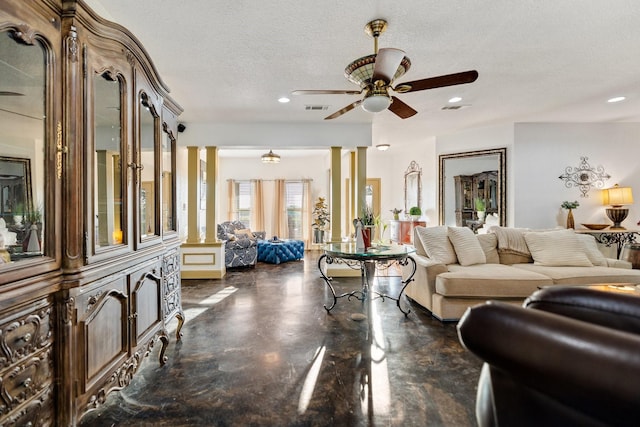 living room with ceiling fan, a textured ceiling, and ornate columns