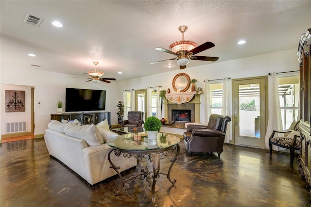 living room featuring ceiling fan, a premium fireplace, and a textured ceiling