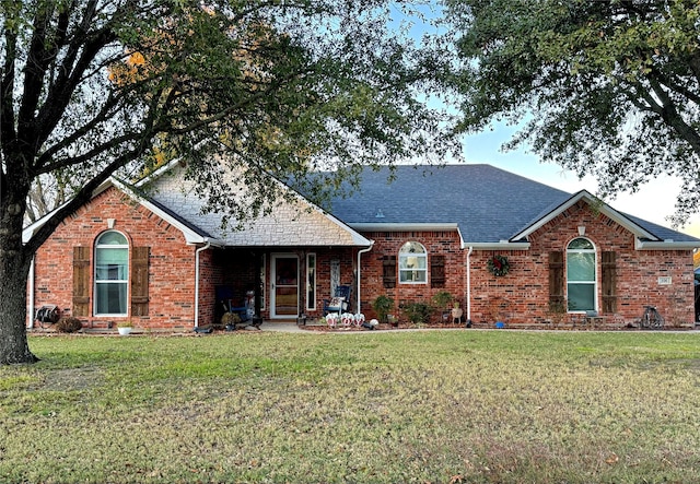 ranch-style house with brick siding, roof with shingles, and a front lawn