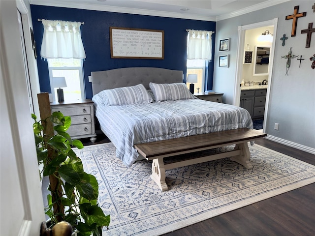 bedroom with connected bathroom, crown molding, baseboards, and wood finished floors