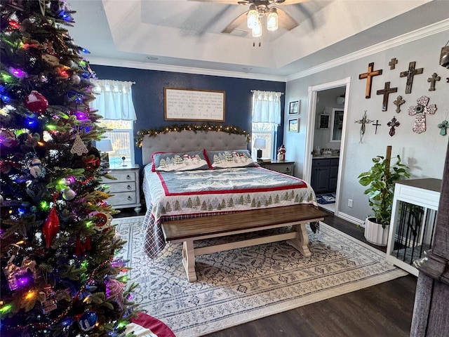 bedroom featuring ensuite bath, ceiling fan, crown molding, hardwood / wood-style floors, and a tray ceiling