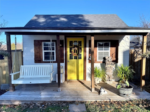 view of outbuilding featuring fence and covered porch