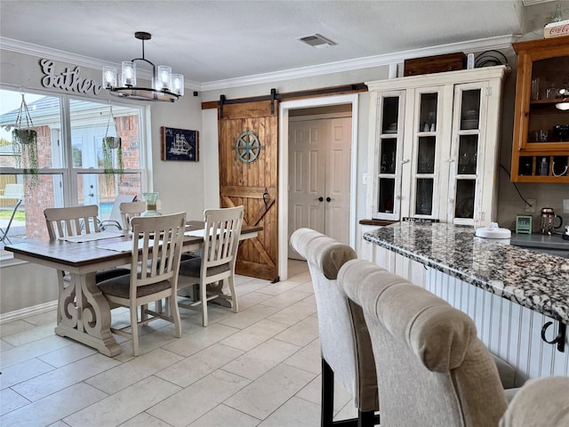 dining area featuring visible vents, ornamental molding, a textured ceiling, a barn door, and an inviting chandelier