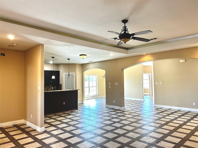 unfurnished living room featuring ceiling fan and a textured ceiling