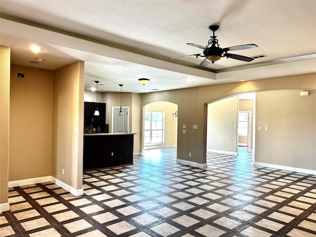 unfurnished living room with ceiling fan and a textured ceiling