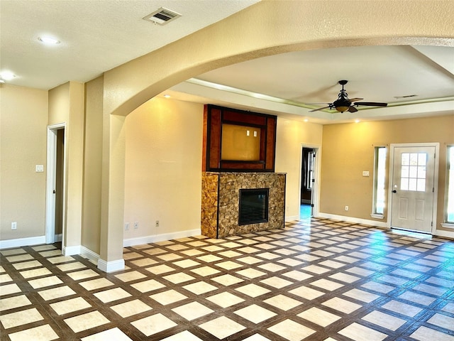 unfurnished living room featuring a textured ceiling, a raised ceiling, and ceiling fan