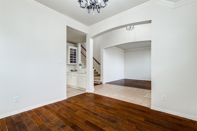 empty room with light hardwood / wood-style flooring, crown molding, and an inviting chandelier