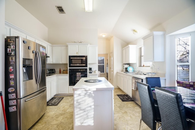 kitchen featuring a center island, white cabinets, stainless steel appliances, and lofted ceiling