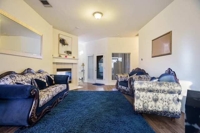 living room with a tile fireplace and dark hardwood / wood-style flooring