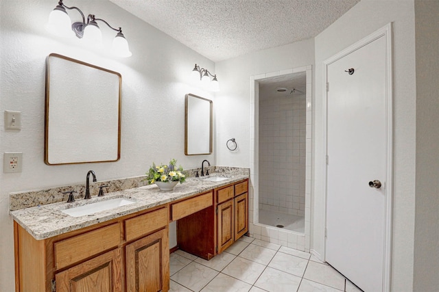 bathroom featuring a tile shower, tile patterned flooring, vanity, and a textured ceiling